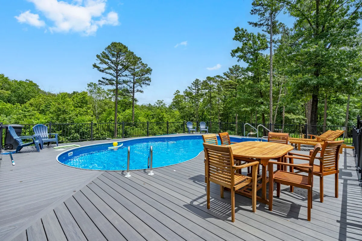 This image highlights a beautiful swimming pool with a dining table and lounge chairs, all set amidst surrounding trees. The setting feels relaxed and cheerful, perfect for both morning and evening outdoor enjoyment.