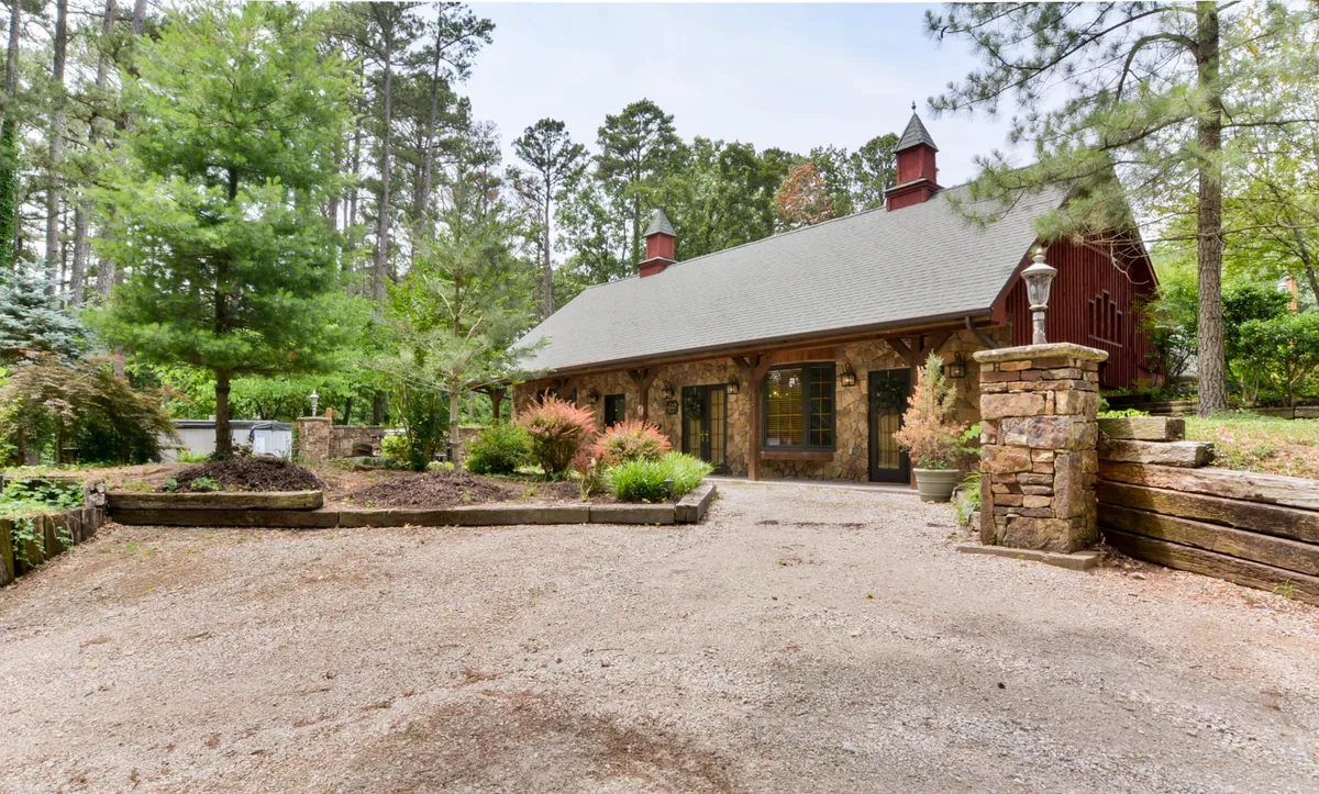 This image highlights the stone facade of The Hiding Place set amongst lush greenery and a gravel driveway. The natural surroundings and open space are prominent, evoking a sense of tranquility and connection to the outdoors, ideal for nature walks and pet-friendly exploration.