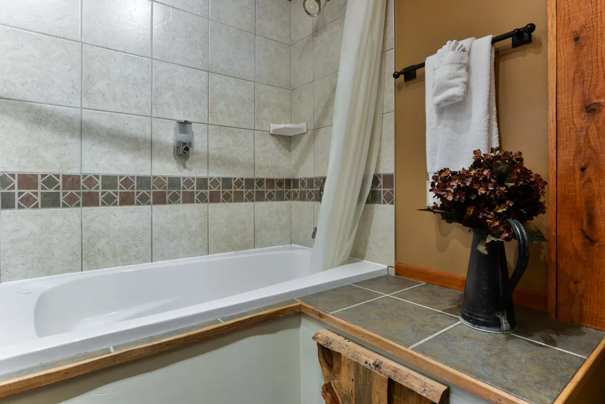 A tranquil bathroom with a standalone bathtub, soft towels, and decorative flowers. The space is designed for relaxation and self-care, offering a soothing retreat for a restorative soak after a long day.