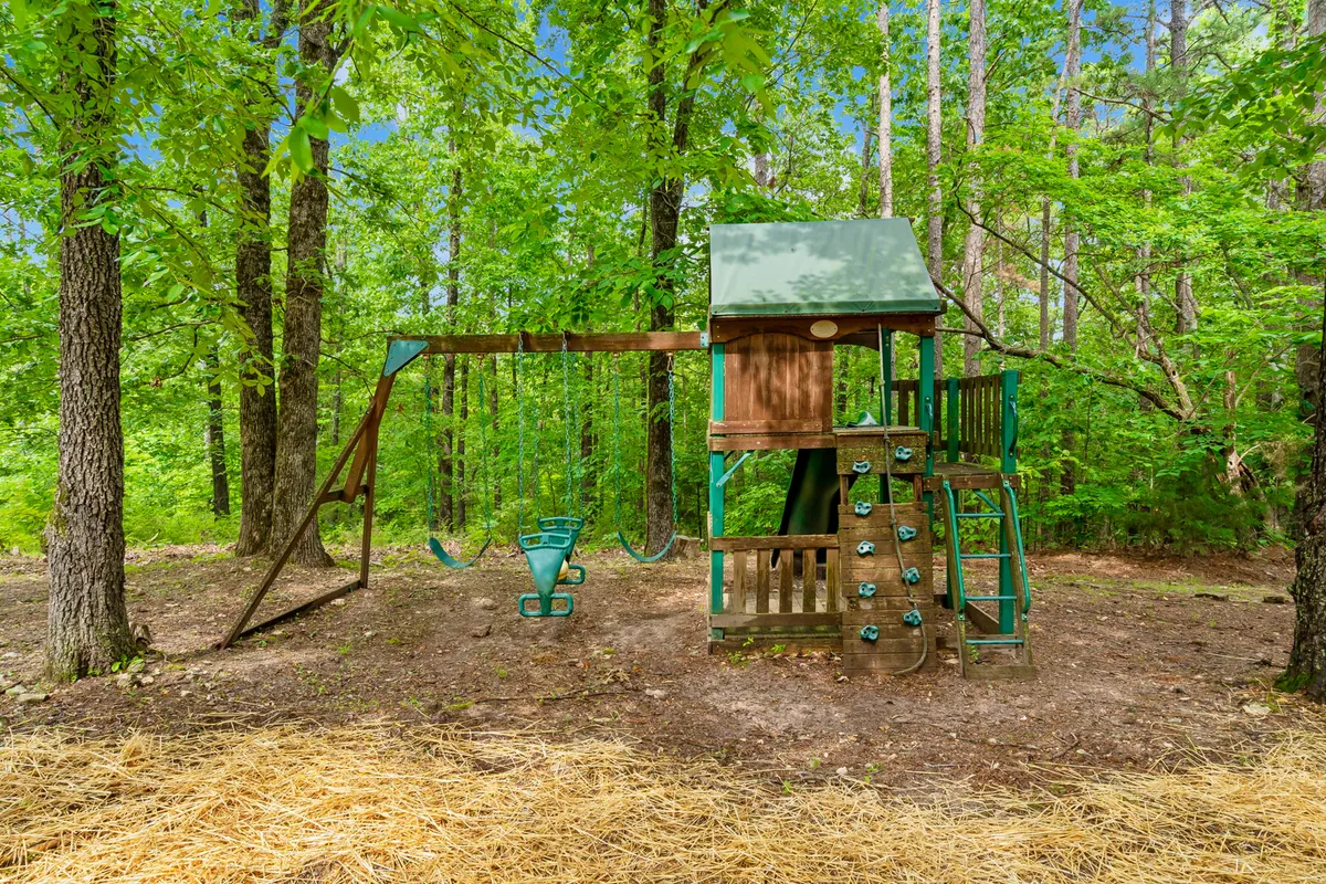 A vibrant outdoor playset with swings and a climbing wall is set on an open lawn, inviting kids and families to enjoy outdoor adventures in a joyful, green environment.