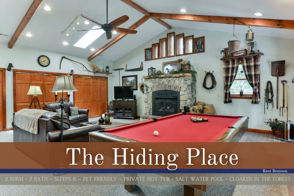 The image showcases a warm, inviting living space featuring a pool table as the centerpiece, a rustic stone fireplace beneath exposed wooden beams, and plush seating arranged for comfort and conversation. The rich wood accents and cozy decor evoke a sense of relaxation and togetherness, perfect for unwinding or playing games with friends and family.